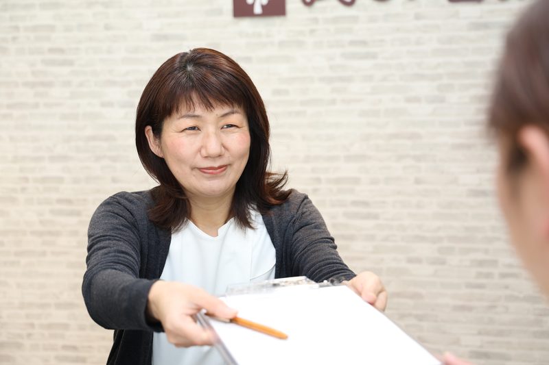 カウンセラー後藤がお客様に問診票をお渡しする様子